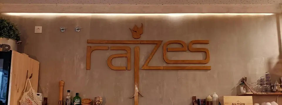 El logotipo de Raizes en madera sobre la pared de la barra